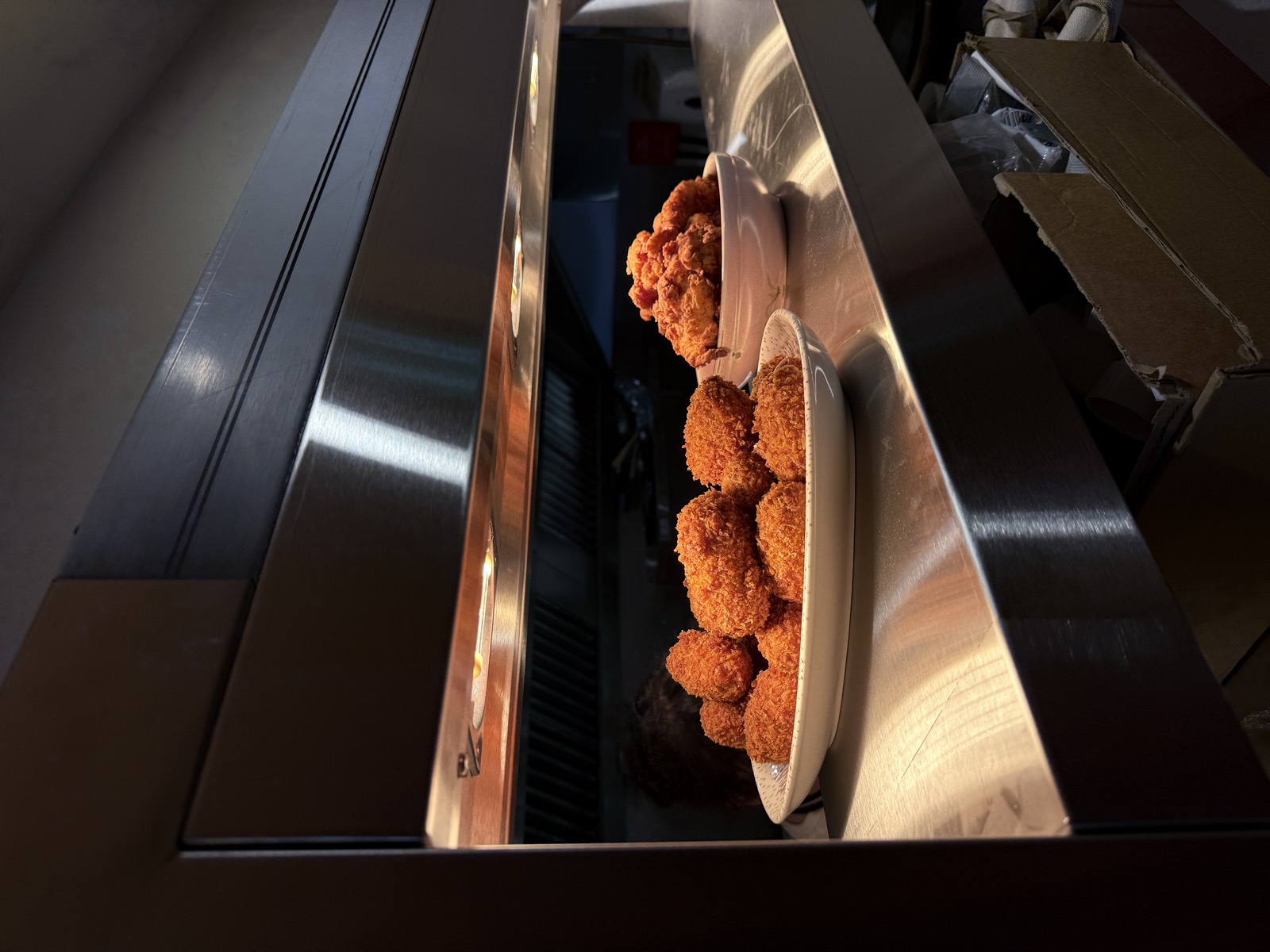 Devilled pheasant croquettes and fried pieces on the steel pass under the heat lamp.