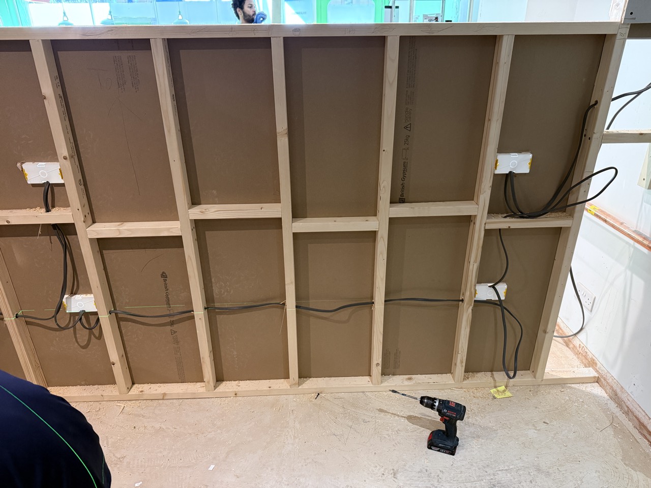 Timber stud framing with first-fix wiring run through it.