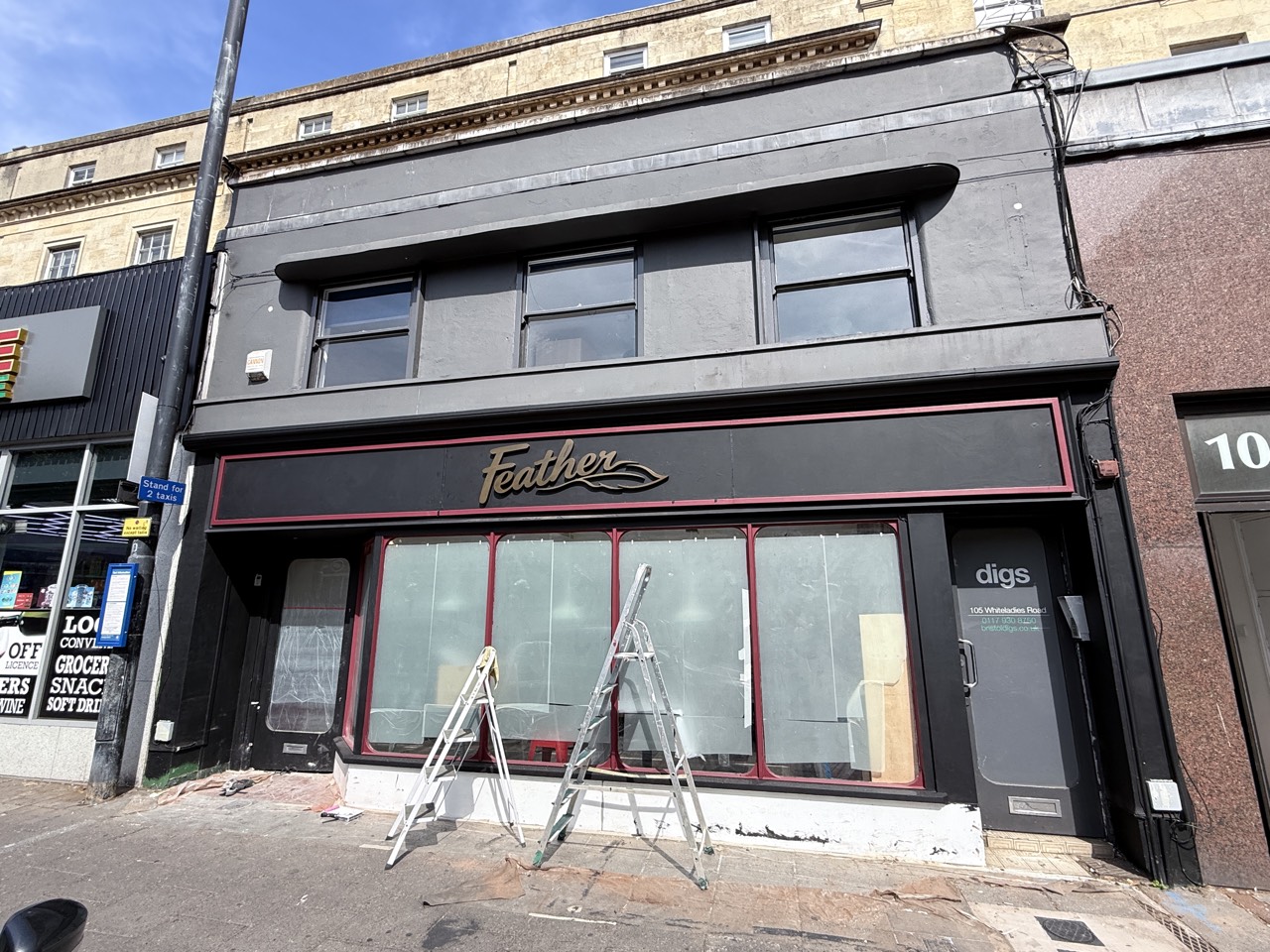 The Feather sign lit above the windows, ladders still on the pavement.