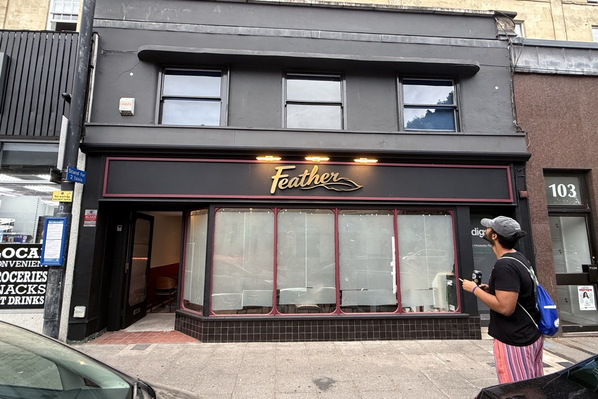 The finished Feather shopfront: black frontage, red window frames, gold script sign.